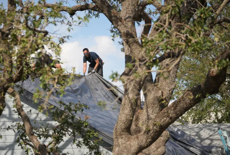 Man putting tarp on roof in Round Rock, TX